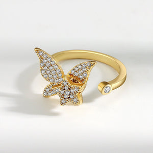 Gold spinner ring with diamond-encrusted butterfly design on a white background