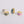 Three gold-rimmed rings with different colored centers on a light gray background