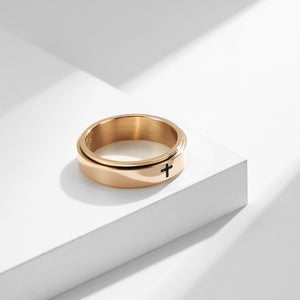 A collection of four rings, two with a black finish and two with a gold plating. Each ring features a cross symbol on the top surface.