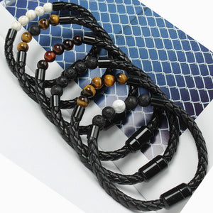 Black braided leather bracelet with beads on a textured surface