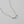 Silver necklace with cube beads spelling 'LOVE' on a light gray background