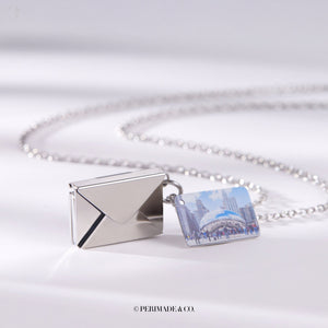 Silver locket necklace with letter and envelope charm on a white background