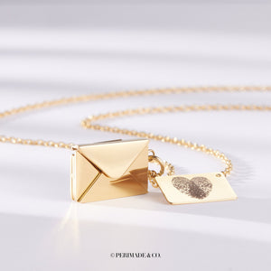 Gold locket necklace with letter and envelope charm on a white background