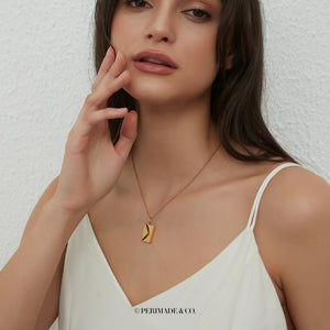 A model wearing a gold locket necklace with letter and envelope charm on a white background