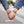 Two hands holding each other with bracelets on, wearing rolled-up jeans.