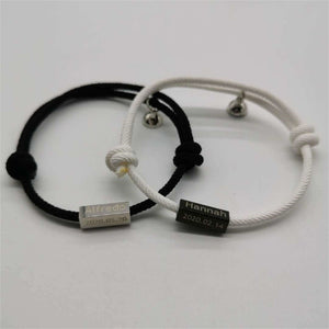Two bracelets, one black and one white, with engraved names on a light gray background.