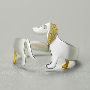 Silver dog-shaped ring with gold accents on a gray background