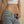 Person wearing a white top and blue jeans with a beige background
