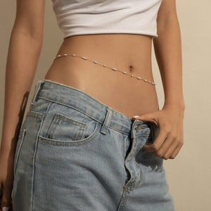 Person wearing a white top and blue jeans with a beige background