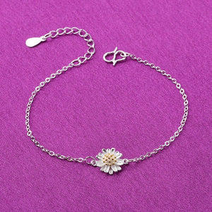 Silver bracelet with a daisy charm on a purple background
