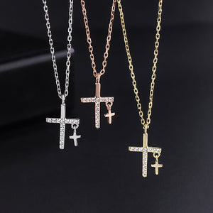 Three cross-shaped pendants on chains against a dark background