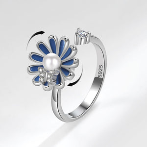 Silver ring with blue flower design on a light gray background