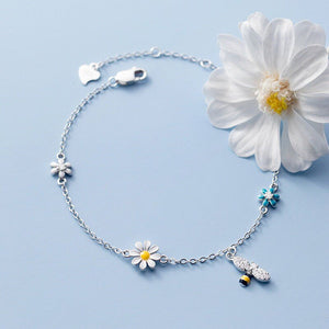 Silver bracelet with floral charms on a light blue background