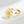 Gold ring with a daisy flower design on a light gray background