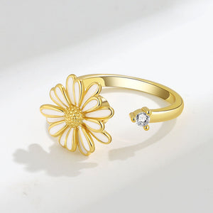 Gold ring with a daisy flower design on a light gray background