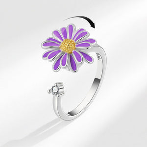 A daisy flower fidget spinner ring with purple petals and a gold center, set on a silver-colored band.