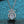 Silver necklace with a round diamond pendant on a textured blue background