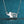 Silver elephant necklace with heart and diamond on a blue glittery background
