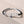 Bracelet with silver antler design and black and white cord on a beige background
