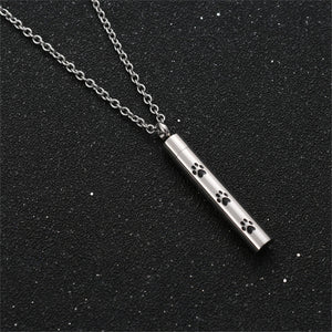 Silver necklace with a cylindrical pendant featuring paw prints on a black background