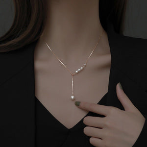 Pearl necklace being worn on a mannequin with a hand adjusting it.