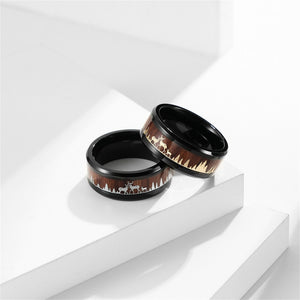 Two black-rimmed rings with nature-themed design on a white surface