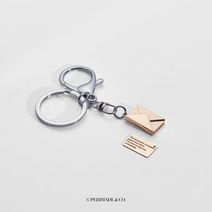 Silver keychain with rose gold letter and envelope charm on a white background, branded 'PERIMADE & CO'.