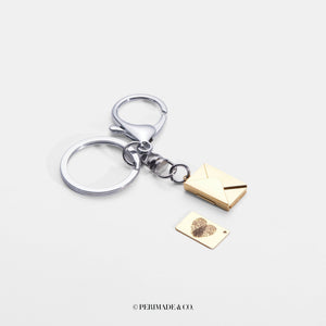 Silver keychain with gold letter and envelope charm on a white background, branded 'PERIMADE & CO'.