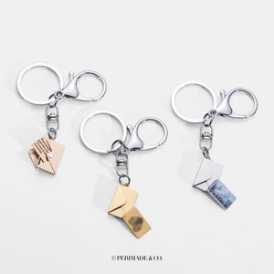 Three silver keychains with letter and envelope charms on a white background, branded 'PERIMADE & CO'.