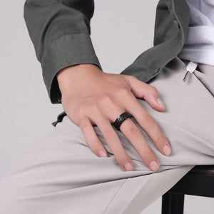 A man wearing a black evil eye spinner band ring