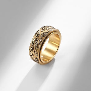Gold evil eye spinner band ring on a white surface
