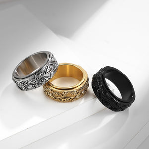 Three evil eye spinner band rings in silver, gold, and black on a white surface