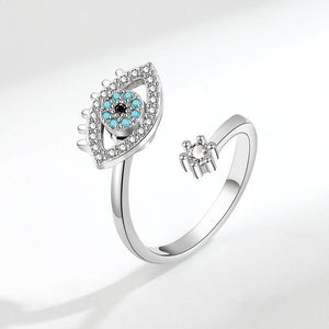 Silver spinner ring with an evil eye design and gemstones on a white background