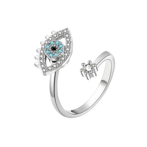 Silver spinner ring with an evil eye design and gemstones on a white background