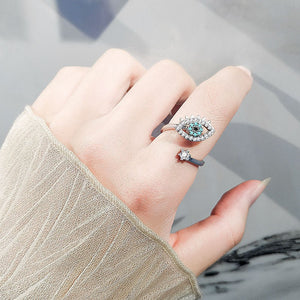 Woman wearing a silver spinner ring with an evil eye design and gemstones on a white background