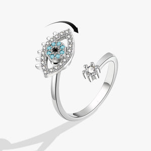 Silver spinner ring with an evil eye design and gemstones on a white background