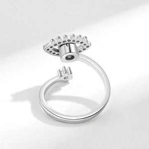 Silver spinner ring with an evil eye design and gemstones on a white background