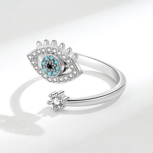 Silver spinner ring with an evil eye design and gemstones on a white background