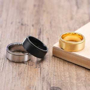 Three rings in gold, black, and silver on a wooden surface