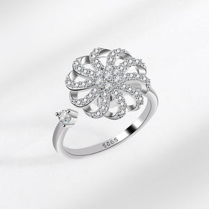 Silver ring with floral design and diamonds on a light gray background