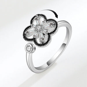 A silver ring with a four leaf clover design and a small cubic zirconia stone on the band.