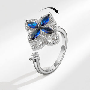 A silver-colored fidget spinner ring with a four leaf clover design, featuring blue and clear cubic zirconia accents.