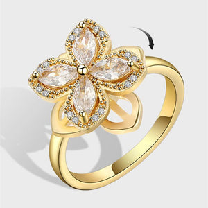 A gold-colored fidget spinner ring with a four leaf clover design, featuring clear cubic zirconia stones.