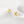 Gold flower-shaped earrings on a white fabric background