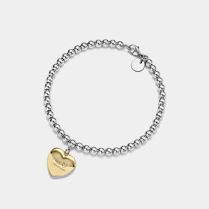 Silver beaded bracelet with a gold heart-shaped locket charm on a light gray background