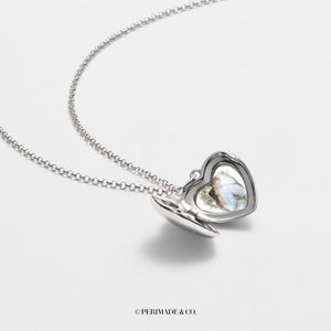Silver bracelet with a heart-shaped locket shown open, featuring a smooth polished exterior and a photo insert inside, displayed on a light gray background