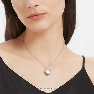 Sterling silver heart locket necklace worn on a delicate chain on a model’s neck.
