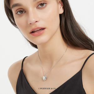 Sterling silver heart locket necklace worn on a delicate chain on a model’s neck.