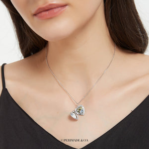 Sterling silver heart locket necklace shown open, worn on a delicate chain on a model’s neck.