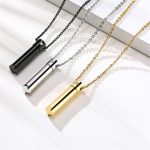Three necklaces with cylindrical pendants in black, silver, and gold on a white background.